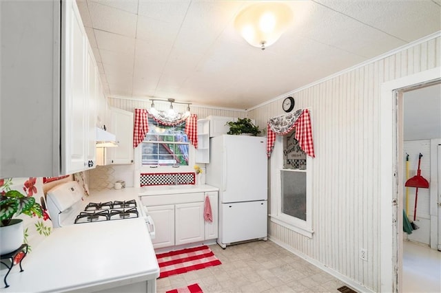 kitchen with white appliances, under cabinet range hood, light countertops, light flooring, and ornamental molding