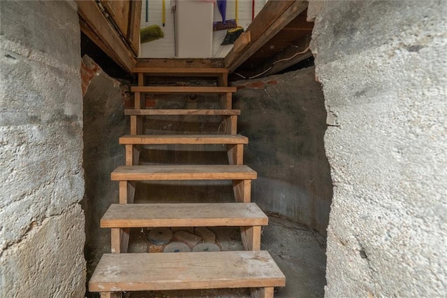 stairway featuring unfinished concrete flooring