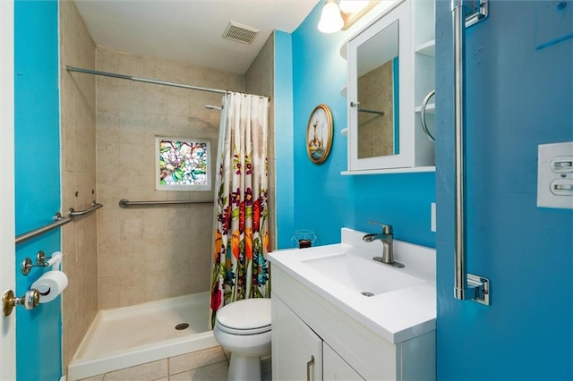 bathroom with tiled shower, toilet, vanity, and tile patterned flooring