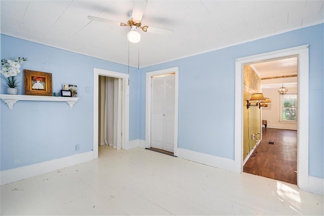 spare room featuring a ceiling fan and baseboards
