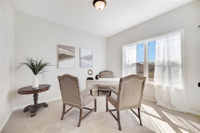 dining space featuring baseboards and light carpet