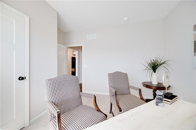 living area featuring baseboards, visible vents, and light colored carpet