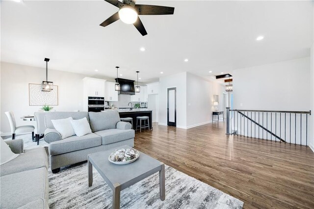 living room featuring a ceiling fan, baseboards, recessed lighting, and wood finished floors