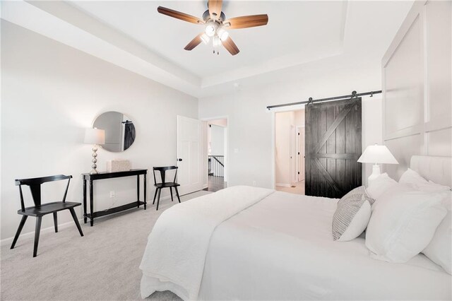 carpeted bedroom with baseboards, a barn door, and a raised ceiling