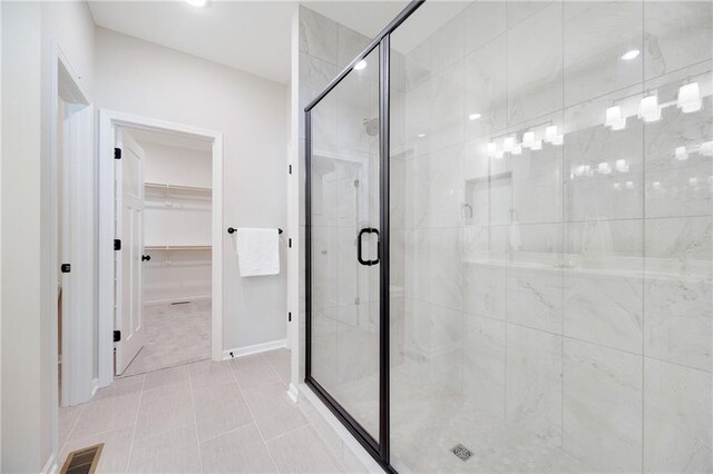 bathroom with a walk in closet, visible vents, tile patterned flooring, a shower stall, and baseboards