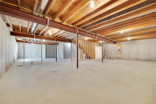 unfinished basement with stairway and electric panel