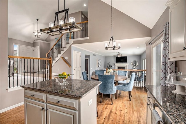kitchen with a chandelier, light wood-style floors, a kitchen island, baseboards, and plenty of natural light