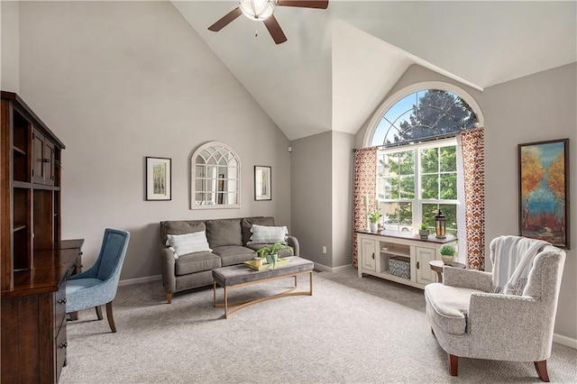 living area featuring a ceiling fan, light colored carpet, baseboards, and high vaulted ceiling