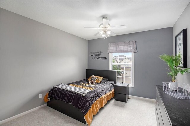 bedroom featuring light carpet, baseboards, and ceiling fan
