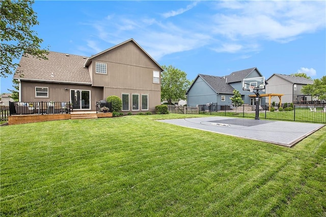 rear view of property featuring basketball court, a wooden deck, a residential view, and roof with shingles