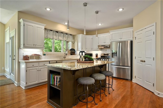 7419 Constance St, Shawnee, KS 66216 - kitchen with stainless steel appliances, a sink, under cabinet range hood, a center island, and decorative backsplash