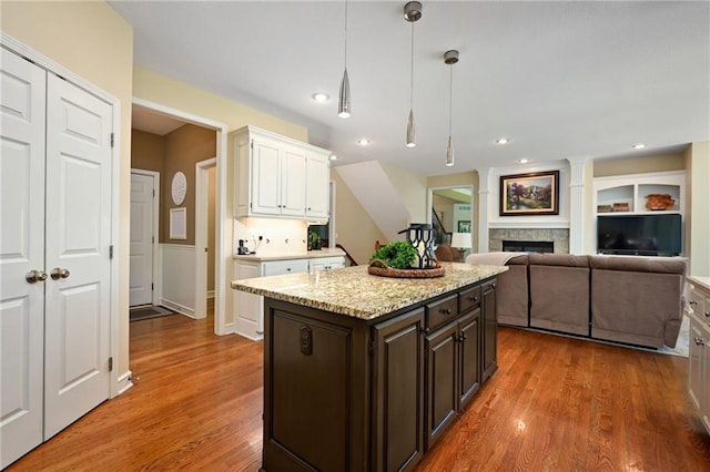 7419 Constance St, Shawnee, KS 66216 - kitchen featuring white cabinetry, dark brown cabinets, wood finished floors, a fireplace, and hanging light fixtures