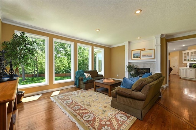 7419 Constance St, Shawnee, KS 66216 - living area with crown molding, wood finished floors, a tiled fireplace, a textured ceiling, and recessed lighting