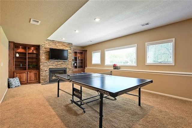 7419 Constance St, Shawnee, KS 66216 - rec room with a textured ceiling, a stone fireplace, carpet flooring, baseboards, and built in shelves