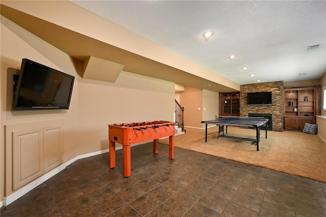7419 Constance St, Shawnee, KS 66216 - recreation room with a stone fireplace, baseboards, dark carpet, recessed lighting, and a textured ceiling