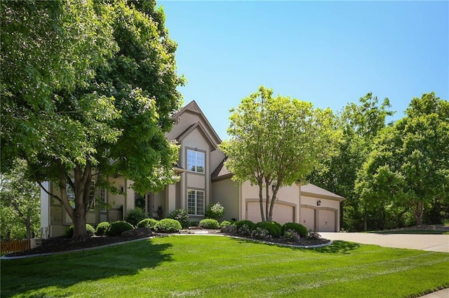 7419 Constance St, Shawnee, KS 66216 - view of property hidden behind natural elements with driveway, a front yard, an attached garage, and stucco siding