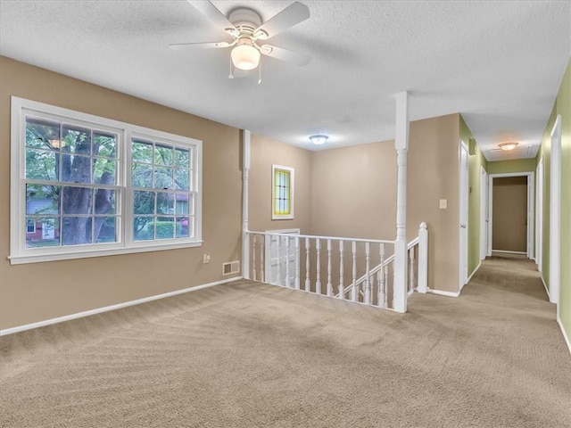 empty room with visible vents, baseboards, a textured ceiling, a ceiling fan, and carpet
