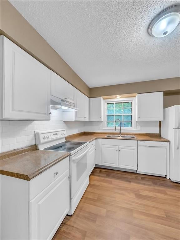 kitchen with white cabinets, a sink, white appliances, a textured ceiling, and under cabinet range hood