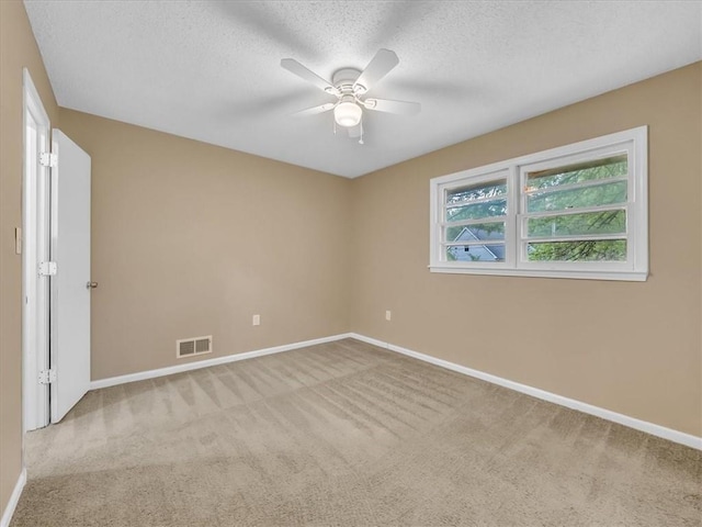 carpeted spare room featuring baseboards, ceiling fan, a textured ceiling, and visible vents