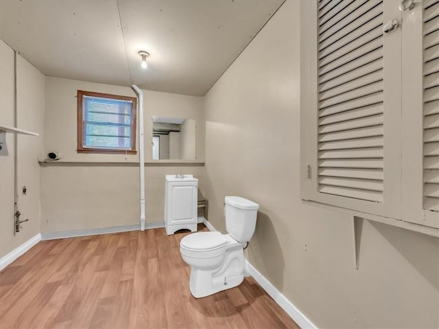 bathroom featuring baseboards, a sink, wood finished floors, and toilet