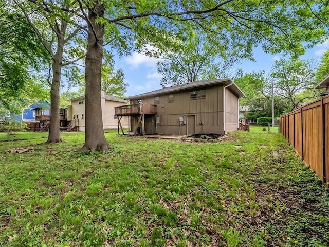 rear view of property featuring fence, a yard, and a wooden deck
