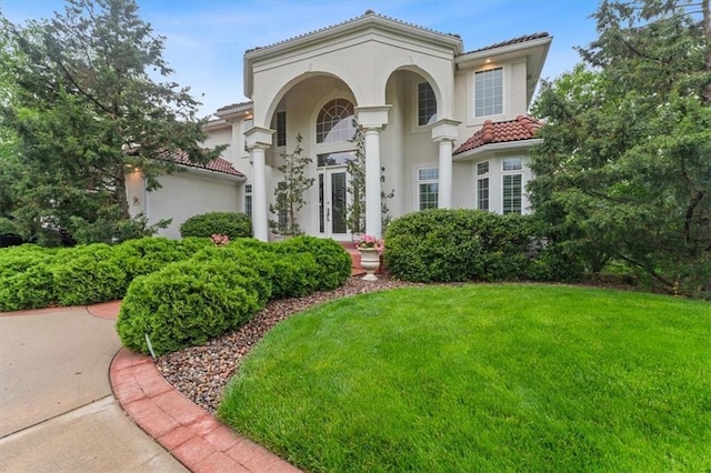 mediterranean / spanish-style home with a tiled roof, a front lawn, and stucco siding