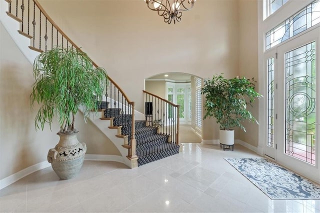 entryway with stairway, a towering ceiling, arched walkways, and baseboards