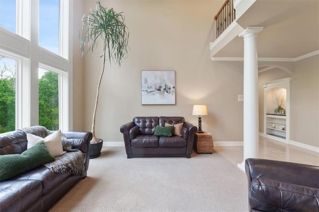 living area with ornate columns, arched walkways, baseboards, a towering ceiling, and carpet floors