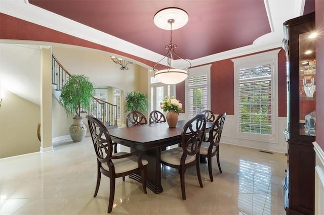 dining room featuring wainscoting, light tile patterned floors, arched walkways, and a decorative wall