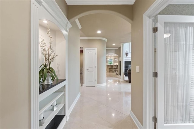 hallway with arched walkways, crown molding, baseboards, light tile patterned flooring, and recessed lighting