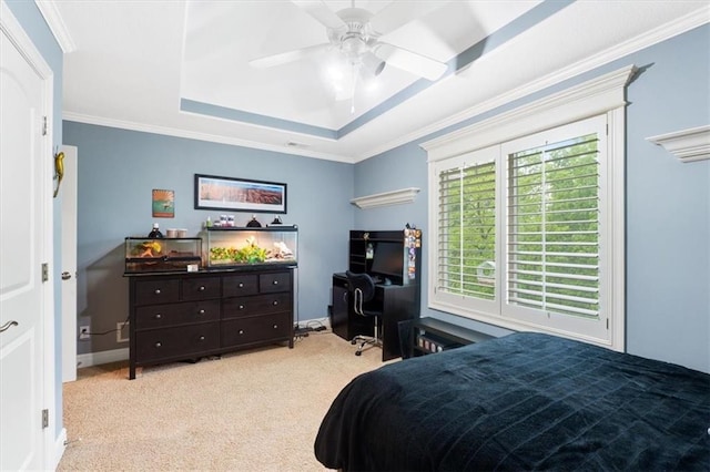 carpeted bedroom with a tray ceiling, crown molding, ceiling fan, and baseboards