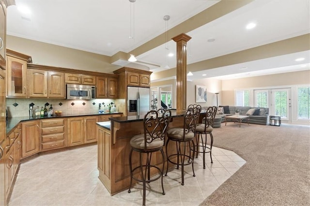 kitchen featuring stainless steel appliances, ornate columns, a breakfast bar area, open floor plan, and light tile patterned floors