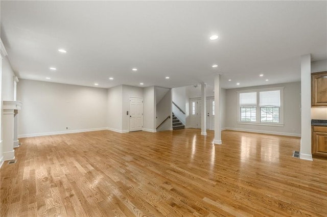 875 Clearview Dr, Lansing, KS 66043 - unfurnished living room featuring recessed lighting, stairs, light wood-style floors, and decorative columns
