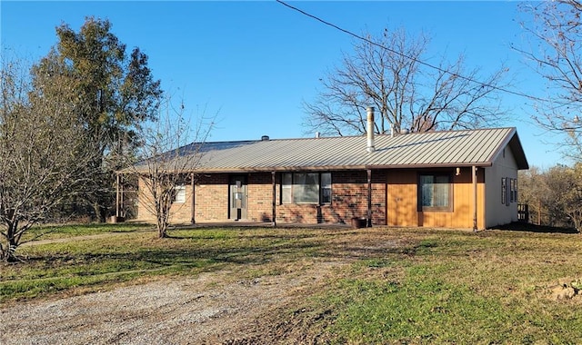 ranch-style home with brick siding, a front yard, and metal roof