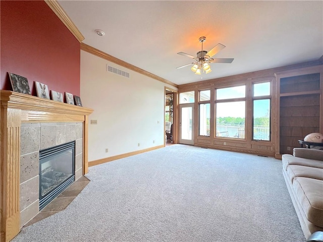carpeted living area with ornamental molding, a tile fireplace, ceiling fan, and baseboards