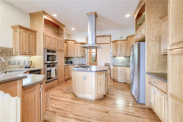 kitchen featuring stainless steel appliances, light brown cabinetry, island range hood, a sink, and decorative backsplash
