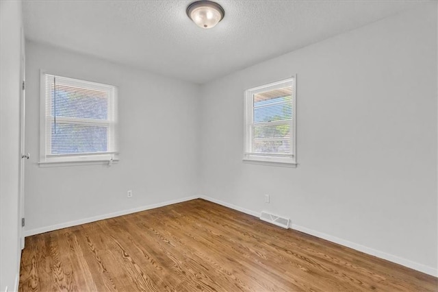 705 NW 88th Ter, Kansas City, MO 64155 - spare room with visible vents, baseboards, a textured ceiling, and wood finished floors