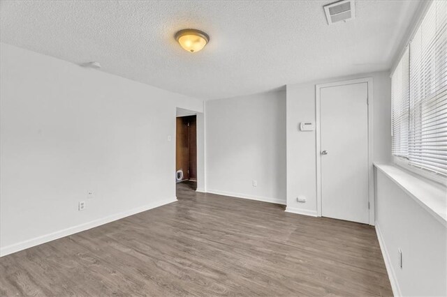 705 NW 88th Ter, Kansas City, MO 64155 - spare room with baseboards, a textured ceiling, visible vents, and wood finished floors