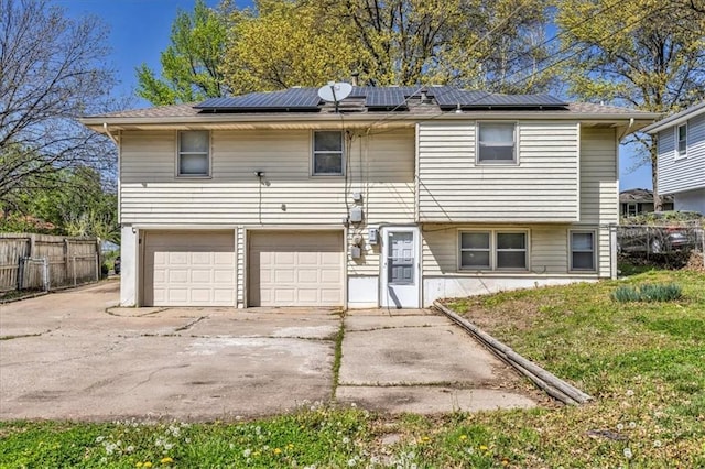 705 NW 88th Ter, Kansas City, MO 64155 - view of front facade with a garage, fence, concrete driveway, and roof mounted solar panels