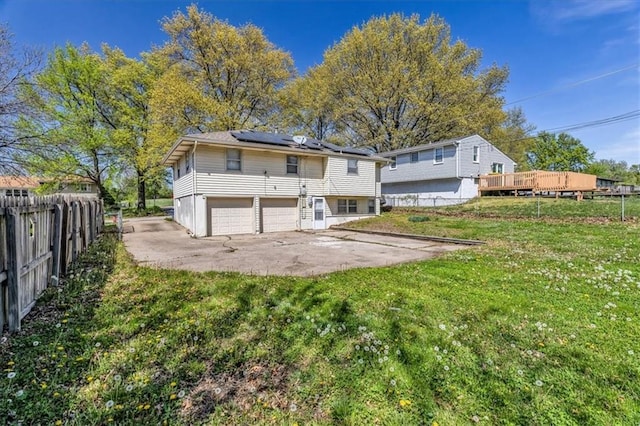 705 NW 88th Ter, Kansas City, MO 64155 - back of house featuring a yard, an attached garage, fence, and solar panels