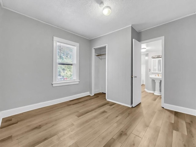 1619 Harvard Ave, Independence, MO 64052 - unfurnished bedroom featuring crown molding, light wood-style flooring, a textured ceiling, and a closet