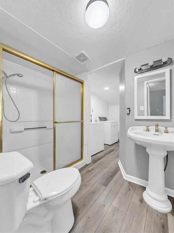 1619 Harvard Ave, Independence, MO 64052 - full bathroom featuring a stall shower, toilet, a textured ceiling, and washer and dryer