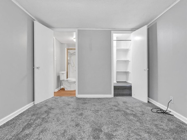 1619 Harvard Ave, Independence, MO 64052 - unfurnished bedroom with carpet flooring, a walk in closet, a textured ceiling, baseboards, and ensuite bathroom