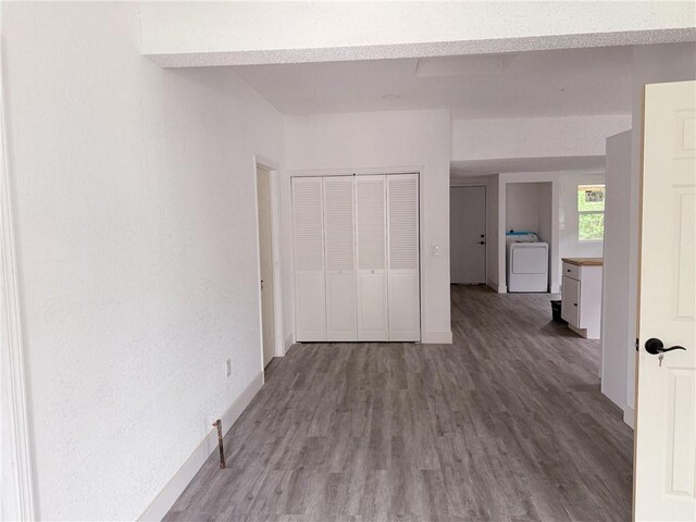 unfurnished room with baseboards, washer / dryer, and wood finished floors