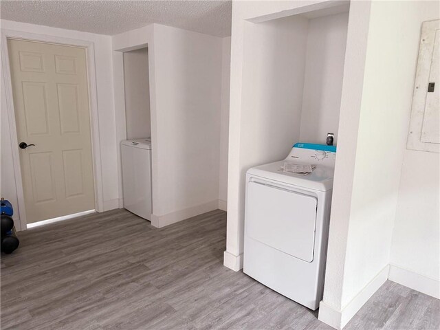 laundry room with laundry area, baseboards, a textured ceiling, and wood finished floors