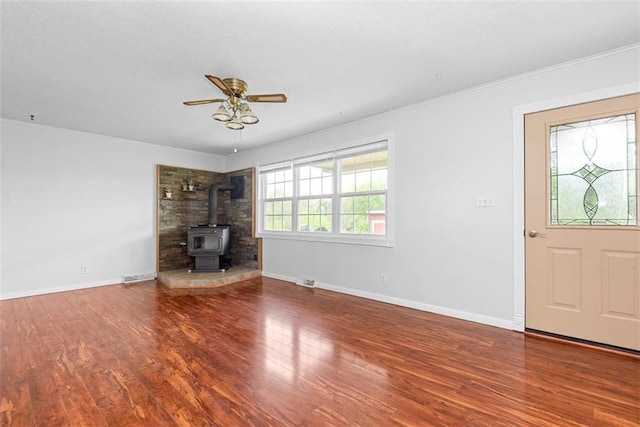 588 NW 105th Rd, Centerview, MO 64019 - unfurnished living room featuring ceiling fan, a wood stove, wood finished floors, and baseboards