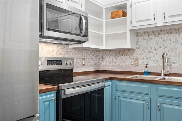 588 NW 105th Rd, Centerview, MO 64019 - kitchen with appliances with stainless steel finishes, blue cabinetry, a sink, backsplash, and white cabinets