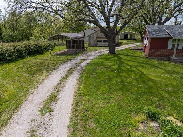 588 NW 105th Rd, Centerview, MO 64019 - view of green lawn featuring driveway, a carport, and an outdoor structure