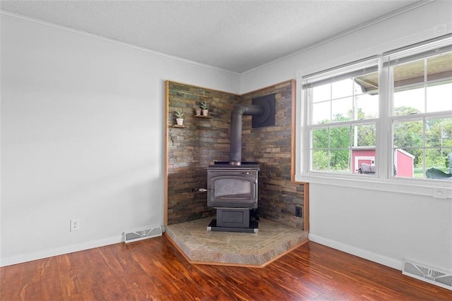 588 NW 105th Rd, Centerview, MO 64019 - living room featuring a wood stove, baseboards, wood finished floors, crown molding, and a textured ceiling