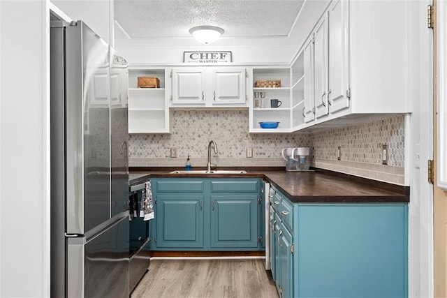 588 NW 105th Rd, Centerview, MO 64019 - kitchen featuring open shelves, freestanding refrigerator, blue cabinetry, a sink, and a textured ceiling